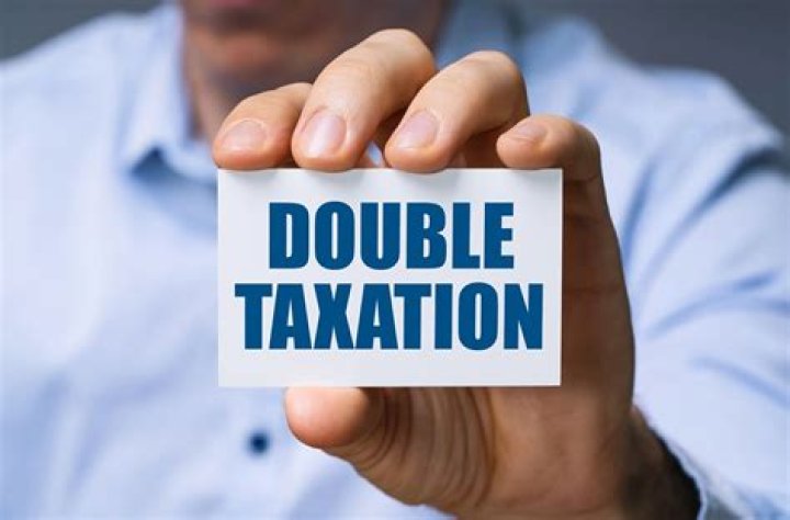 How does a tax treaty eliminate double taxation?